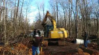 Deere excavator putting in concrete pipe