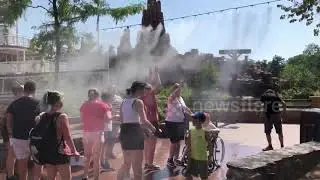 Families visiting Disneyland Paris cool down under water mist during European heatwave