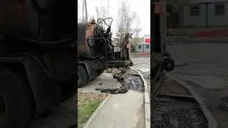 Битумовоз поливает основание тротуара битумом. Ремонт дороги. Специальная дорожная техника.