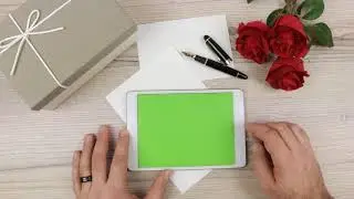 a man using a Tablet PC with green empty screen on a wooden table - free use