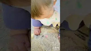 Baby finds something funny in the sand