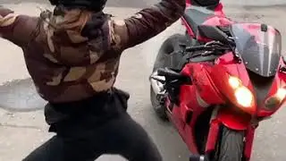 мотоциклистка танцует, пока греется мотоцикл 