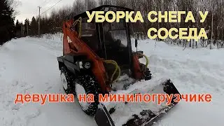 Уборка снега во дворе соседа. Девушка управляет трактором UNC060